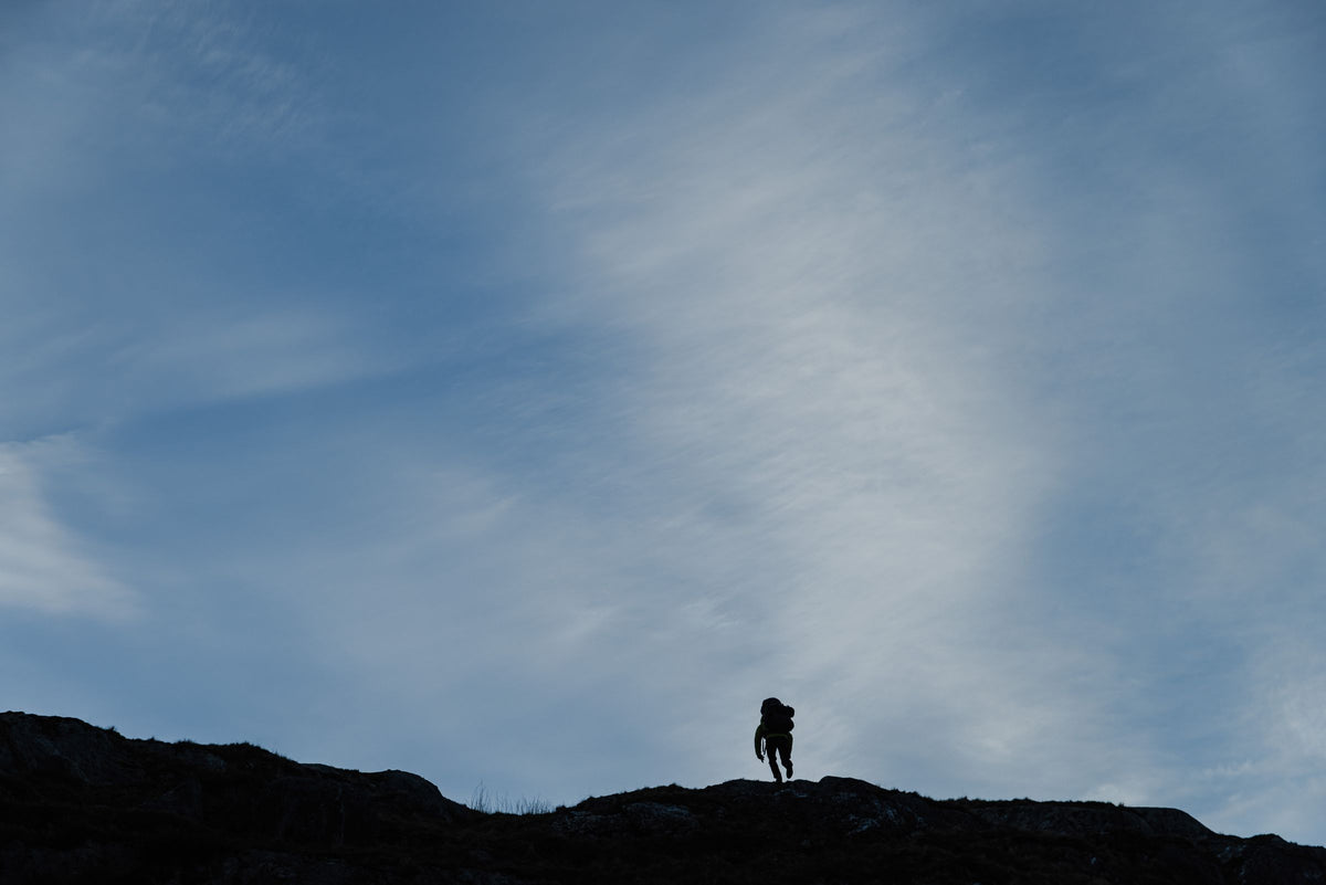 Fjellvandrer i silhuett på en fjellrygg under stor himmel